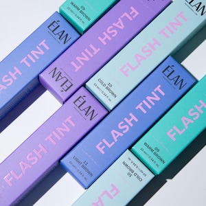 Puede incluir: Un conjunto de seis frascos de tinte para pestañas en varios tonos de azul y verde. Los frascos están etiquetados con el nombre de la marca "ÉLAN" y el nombre del producto "FLASH TINT". Los frascos están etiquetados con el nombre del tono y el volumen: 09 Warm Brown, 10 Cold Brown, 11 Light Brown.