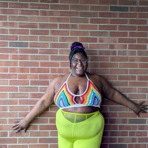 May include: A rainbow crochet top with a keyhole design and neon green pants. The top features a vibrant array of colors, including red, orange, yellow, green, blue, and purple. The pants are a bright, eye-catching shade of green.