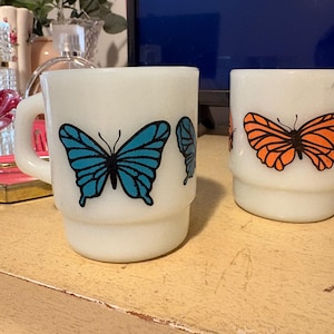 Tazas de vidrio opalino Fire King con forma de mariposa en azul y naranja, apilables, marca Anchor Hocking (alguna imperfección en el azul).