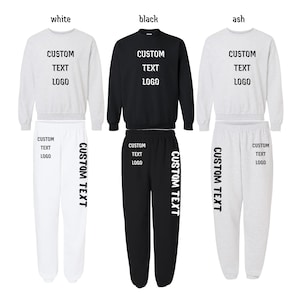 May include: Three matching sweat suits in white, black, and ash colors. Each set includes a crew neck sweatshirt and sweatpants. The text "CUSTOM TEXT LOGO" is printed on the front of the sweatshirts and on the left leg of the sweatpants.