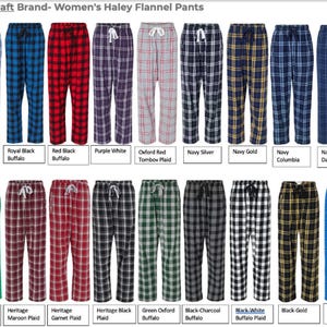May include: A collection of women's Haley flannel pants in various plaid patterns and colors. Colors include blue, red, purple, gray, navy, gold, green, black, and maroon. Each pair has a drawstring waist.