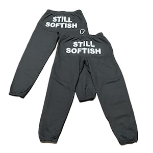 May include: Two pairs of gray sweatpants with the text "STILL SOFTISH" printed in white on the back.