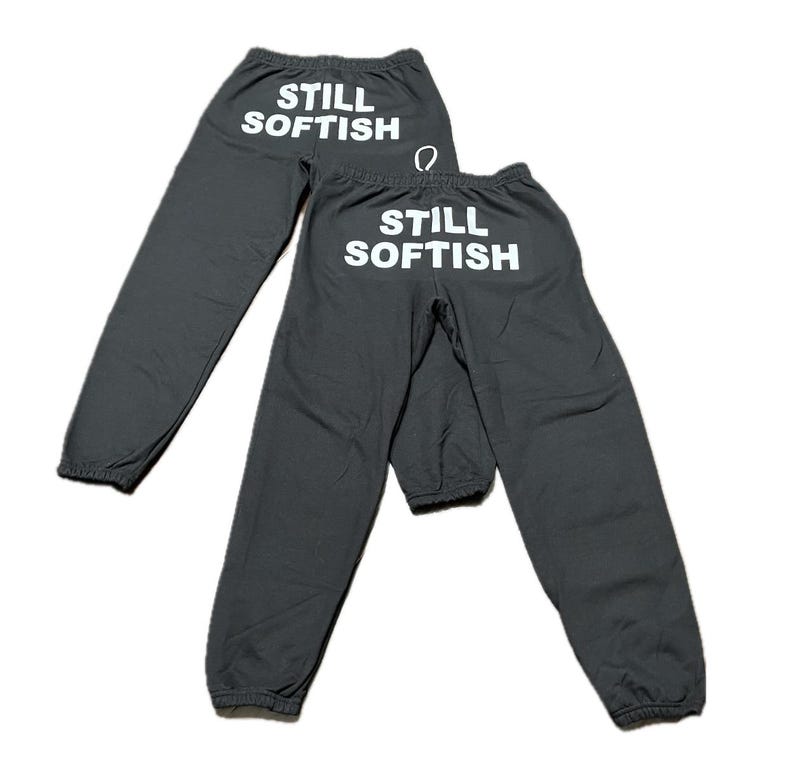 May include: Two pairs of gray sweatpants with the text "STILL SOFTISH" printed in white on the back.