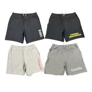 May include: Four pairs of athletic shorts with elastic waistbands and drawstrings. Two pairs are black, one with white text reading BABA and one with yellow text reading COHIBA BROTHERS. Two pairs are gray, one with red text reading I love you Eli and one with white text reading Godzilla.