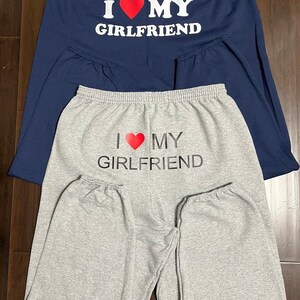 May include: Two pairs of sweatpants, one gray and one navy blue, with the text "I love my girlfriend" printed on the back.