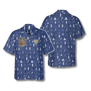 May include: Blue button-down shirt with a repeating pattern of white symbols and shapes. The shirt features a Masonic emblem and the number 857 in gold. The words "YOUR LODGE NAME" are above the emblem.