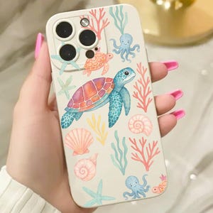 Puede incluir: Una funda blanca para teléfono con un diseño de acuarela de tortugas marinas, estrellas de mar, conchas marinas y corales. La funda tiene un diseño protector con recortes para la cámara y los botones. La funda con temática marina tiene una estética colorida y caprichosa.