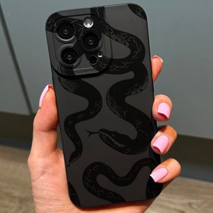 May include: Black phone case with a dark grey snake pattern. The case has a matte finish and a camera cutout. The snake design is a repeating pattern across the back of the phone case.
