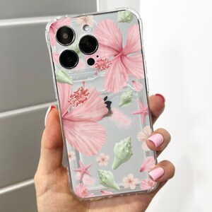 Può includere: Custodia trasparente per telefono con un design floreale con fiori di ibisco rosa, conchiglie verdi e stelle marine. La custodia è trasparente, consentendo di vedere il colore del telefono. Il design ha un effetto acquerello.