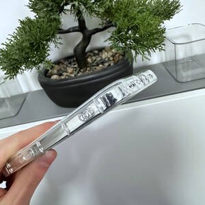 May include: A clear phone case with the Audi logo printed on the back.