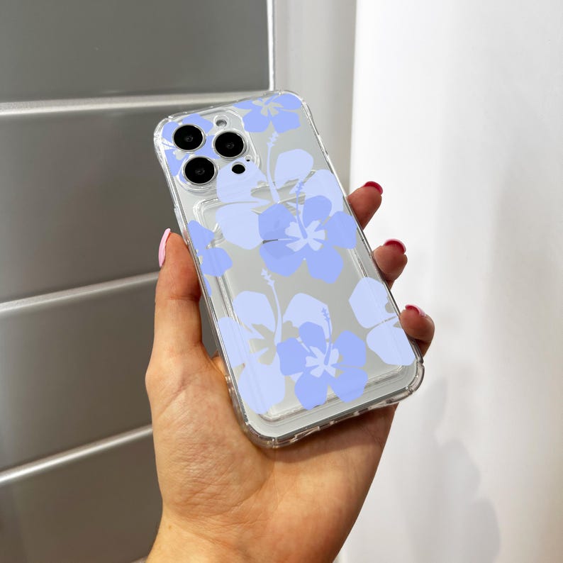 May include: A clear phone case with a light blue floral design. The case has a raised lip around the camera lens to protect it from scratches.