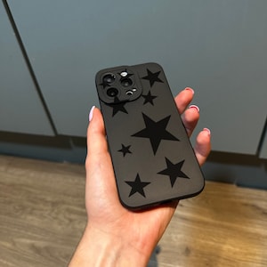May include: A black phone case with a black star pattern. The case has a cutout for the camera lens.