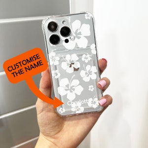 May include: Clear phone case with a white hibiscus flower design and the name "Charlotte" printed on the bottom.