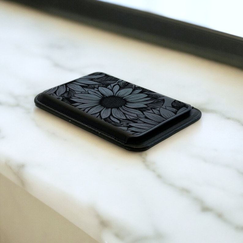 May include: A black leather phone case with a sunflower design.