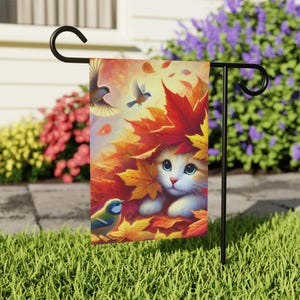May include: A cute orange and white cat peeks out from a pile of colorful autumn leaves. Two blue birds fly overhead and a bluebird sits on a branch. This is a garden flag with a fall theme.