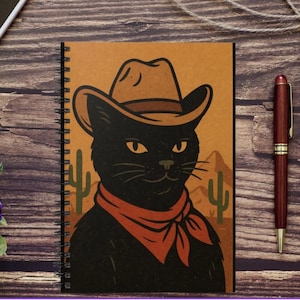 Op de afbeelding: Een zwarte kat met een bruine cowboyhoed en een rode bandana. De kat staat tegen een woestijn achtergrond met cactussen.