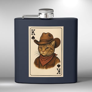 Puede incluir: Una petaca de metal azul con una ilustración en blanco y negro de un gato con un sombrero de vaquero y un pañuelo. El gato sostiene una carta de juego que dice "K" y tiene un símbolo de pica.