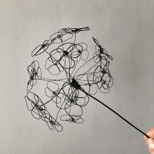 May include: A black wire sculpture of a flower with multiple petals. The sculpture is made of thin wire and has a delicate, airy appearance.