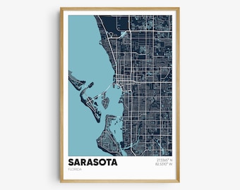 May include: A framed map of Sarasota, Florida, with a blue and white color scheme. The map shows the city's streets and waterways. The text "SARASOTA" and "FLORIDA" is printed below the map, along with the coordinates "27.3365° N 82.5310° W".
