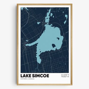 May include: A blue and white map print of Lake Simcoe, Ontario, Canada. The map shows the lake and surrounding area with roads and other features. The text "LAKE SIMCOE" is printed in white at the bottom of the map, along with the coordinates "44.4636° N 79.3353° W".