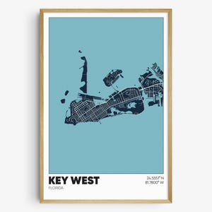 May include: A blue and white map print of Key West, Florida. The map shows the streets and waterways of the island. The text "KEY WEST" and "FLORIDA" are printed below the map. The coordinates "24.5555° N 81.7800° W" are printed in the upper right corner.