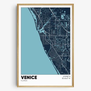 May include: A framed map of Venice, Florida, with a blue and light blue color scheme. The map shows the city's streets and waterways. The text "VENICE, FLORIDA" and the coordinates "27.0998° N 82.4543° W" are printed below the map.