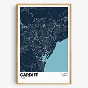 May include: A navy blue and light blue map print of Cardiff, Wales. The map shows the city's streets and coastline. The text "CARDIFF" and "WALES" are printed below the map, along with the coordinates "51.4833° N, 3.1681° W".