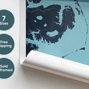 May include: A close-up of a rolled up poster featuring a detailed map of a coastal area. The map is printed on a light blue background with dark blue lines and shapes. The poster is rolled up and partially unrolled, revealing a white edge.