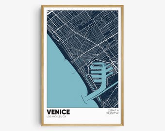 May include: A blue and white map print of Venice, California. The map shows the streets and the coastline. The text "VENICE" and "LOS ANGELES, CA" is at the bottom of the map. The coordinates "33.9941° N 118.4527° W" are at the top right of the map.