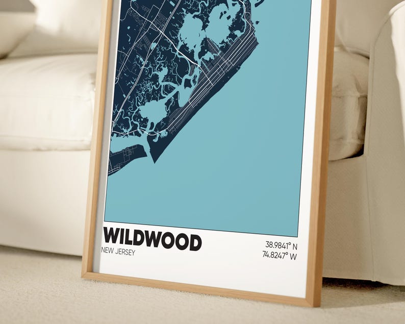 May include: A framed map of Wildwood, New Jersey, with a blue and white color scheme. The map shows the city's streets and waterways. The text "WILDWOOD" and "NEW JERSEY" is printed in black at the bottom of the map. The coordinates "38.9841&deg; N 74.8247&deg; W" are printed in black below the text.