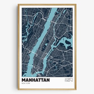May include: A map of Manhattan, New York City, with blue and white lines representing streets and waterways. The map is framed in a light wood frame. The text "MANHATTAN" and "NEW YORK" is printed in black at the bottom of the map. The coordinates "40.7685° N 73.9822° W" are printed in black in the top right corner of the map.