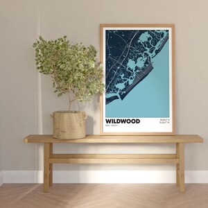 May include: A framed map print of Wildwood, New Jersey, with a blue and white color scheme. The map is displayed on a wooden shelf with a potted plant.