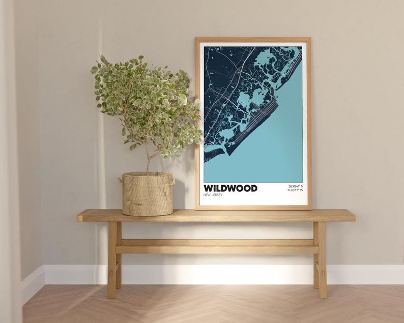 May include: A framed map print of Wildwood, New Jersey, with a blue and white color scheme. The map is displayed on a wooden shelf with a potted plant.