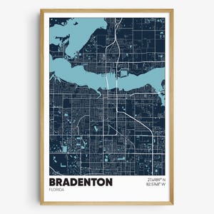 May include: A map print of Bradenton, Florida, with a dark blue background and light blue water features. The city streets are shown in white lines. The text "Bradenton, Florida" and the coordinates "27.4989° N 82.5748° W" are printed at the bottom of the map.