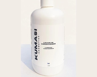 Op de afbeelding: Witte plastic fles leave-in conditioner met het label "KUMASI - COSMETICS - LEAVE IN CONDITIONER - LAISSEREN CONDITIONNEUR" met een zwart label en een zwarte dop. De fles is 12 oz.