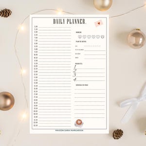 Peut inclure: Un planificateur quotidien crème avec le texte "DAILY PLANNER." et des sections pour l'humeur, le plan de repas et les priorités. Le planificateur comprend une illustration de tasse à café et le texte "MAISON SARA MARGARIDA."