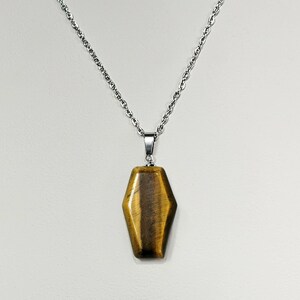 May include: A gold and brown tiger's eye stone pendant on a silver chain necklace.