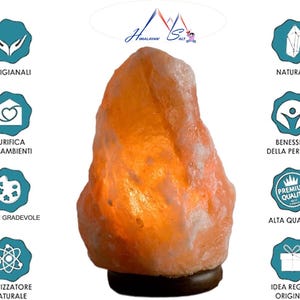Puede incluir: Una l&aacute;mpara de sal del Himalaya con una superficie rugosa de color naranja-rosa. La l&aacute;mpara se asienta sobre una base marr&oacute;n oscuro. El texto en la imagen incluye "Himalayan Salt", "Artigianali", "Purifica Gli Ambienti", "Luce Gradevole", "Ionizzatore Naturale", "Naturali", "Benessere Della Persona", "Alta Qualita'" e "Idea Regalo Originale".