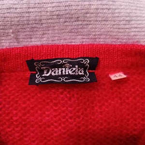 Puede incluir: Su&eacute;ter de punto rojo con una etiqueta negra que dice "Daniela" y una etiqueta de talla que dice "44".
