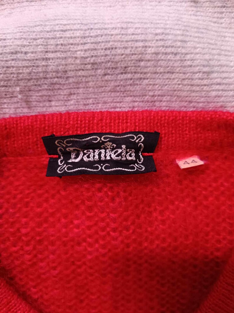 Puede incluir: Su&eacute;ter de punto rojo con una etiqueta negra que dice "Daniela" y una etiqueta de talla que dice "44".