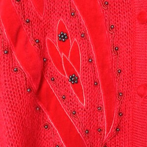 Puede incluir: Su&eacute;ter de punto rojo con un dise&ntilde;o de terciopelo y adornos de cuentas negras.
