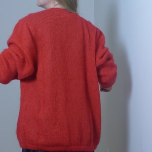 Puede incluir: Un c&aacute;rdigan de punto rojo de manga larga y corte holgado.
