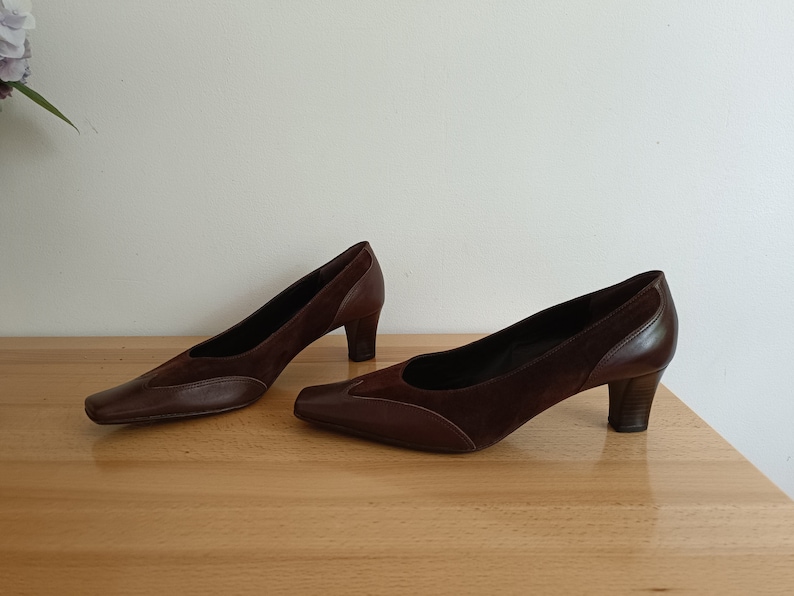 May include: A pair of brown suede and leather pumps with a pointed toe and a medium heel.