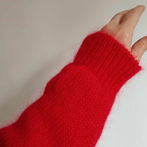 Puede incluir: Primer plano de una manga de su&eacute;ter de punto rojo con textura peluda.