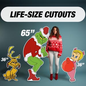 May include: Life-size cutouts of cartoon characters, including a 165cm Grinch in a Santa suit, a 91cm Max, and a 91cm Cindy Lou Who holding a red ornament. A woman in a red sweater and white trousers stands between the cutouts.