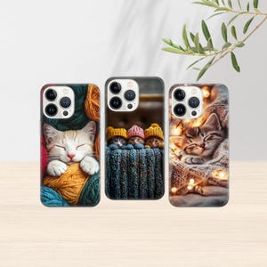 May include: Three phone cases featuring adorable cat designs. One case shows a sleeping kitten nestled in yarn, another features three kittens wearing hats, and the third depicts a kitten wrapped in a blanket with fairy lights.