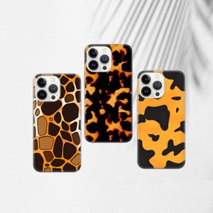 May include: Three phone cases with animal print designs. One case has a giraffe pattern in brown and tan. The second case has a tortoiseshell pattern in black and orange. The third case has an orange and black spotted pattern.