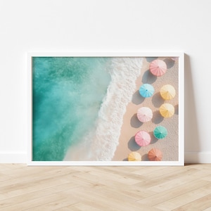 May include: An aerial view of a sandy beach with turquoise water and a row of colorful umbrellas in pastel shades of pink, blue, yellow, and green.