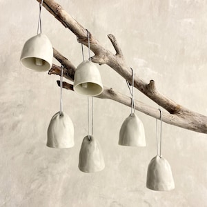 Adorno navideño de porcelana con forma de campana, esmalte moteado y cascabel.