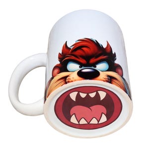 Può includere: Tazza in ceramica bianca con un'immagine a cartoni animati del Diavolo della Tasmania. La tazza ha un manico bianco e un interno bianco. Il Diavolo della Tasmania è raffigurato con pelliccia rossa, occhi blu e muso marrone.